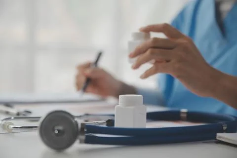 Stethoscope and background doctor using laptop at desk in clinic working on.. Stock Photos