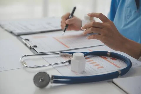 Stethoscope and background doctor using laptop at desk in clinic working on.. Stock Photos