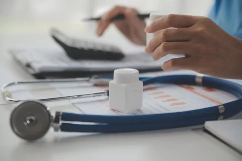 Stethoscope and background doctor using laptop at desk in clinic working on.. Stock Photos