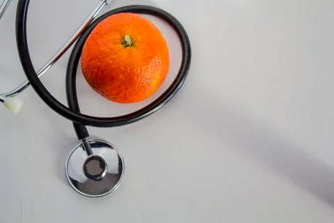 Stethoscope and orange on white table. Top view and copy space Stock Photos