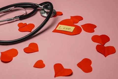 Stethoscope and paper hearts create a display of love on a pink surface Stock Photos