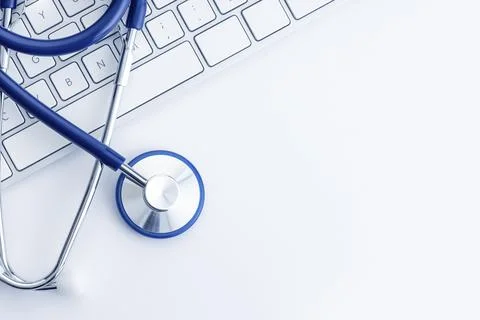 Stethoscope on computer keyboard on white desk. Online health care or Stock Photos