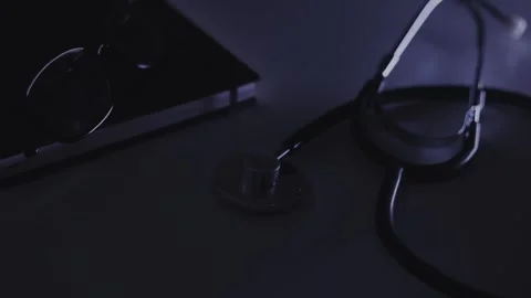 Stethoscope, diary, glasses lie on the table with a blue flashing light Video stock 244599325