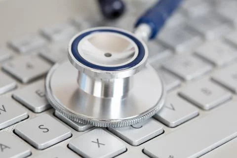Stethoscope head lying on silver keyboard closeup Stock Photos