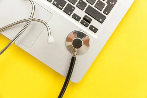 Stethoscope keyboard laptop computer isolated on yellow background. Modern .. Stock Photos