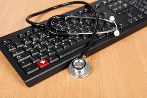 Stethoscope left draped over a computer keyboard on a desk Stock Photos