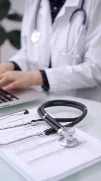 Stethoscope is lying on the glass table while doctor woman is working with 스톡 사진