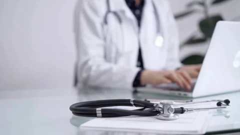The stethoscope is lying on the table beside a doctor who is using a laptop Stock Footage 265667523