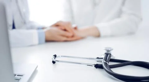 Stethoscope lying on the tablet computer in front of a doctor and patient Stockfoto's