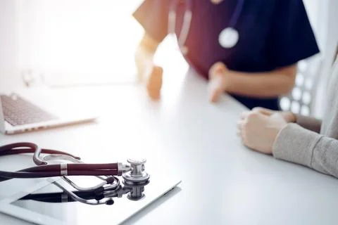 Stethoscope lying on the tablet computer in front of a doctor and patient at the Foto stock