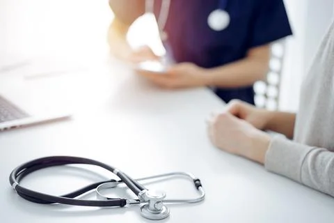 Stethoscope lying on the tablet computer in front of a doctor and patient at the Photos