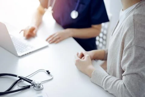 Stethoscope lying on the tablet computer in front of a doctor and patient using Stock Photos