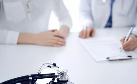Stethoscope lying on the tablet computer in front of a doctor and patient Stockfoto's