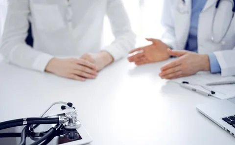 Stethoscope lying on the tablet computer in front of a doctor and patient Stockfoto's