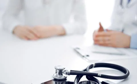 Stethoscope lying on the tablet computer in front of a doctor and patient Stock Photos