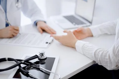 Stethoscope lying on the tablet computer in front of a doctor and patient Stock Photos