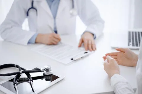 Stethoscope lying on the tablet computer in front of a doctor and patient Stockfoto's