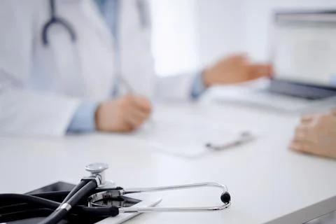 Stethoscope lying on the tablet computer in front of a doctor and patient Stock Photos