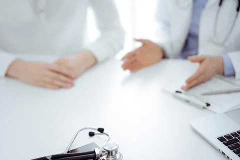 Stethoscope lying on the tablet computer in front of a doctor and patient 库存照片