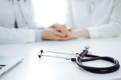 Stethoscope lying on the tablet computer in front of a doctor and patient Stock Photos