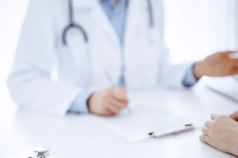 Stethoscope lying on the tablet computer in front of a doctor and patient 库存照片