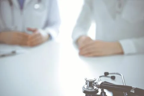 Stethoscope lying on the tablet computer in front of a doctor and patient Stock Photos