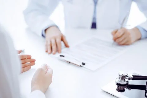 Stethoscope lying on the tablet computer in front of a doctor and patient Stock Photos