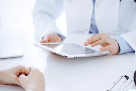 Stethoscope lying on the tablet computer in front of a doctor and patient Фото