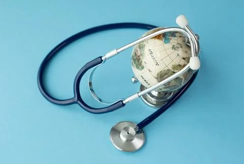 A stethoscope is next to a globe. The globe is white and has a blue border Stock Photos