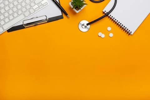 Stethoscope with notebook and pen in doctors desk Stock Photos