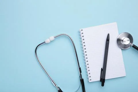 Stethoscope with notebook on blue background. Top view with place for your te Stock Photos