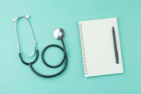 Stethoscope with notepad on green background. Stock Photos