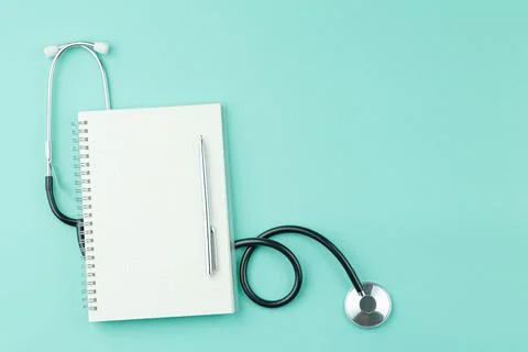 Stethoscope with notepad on green background. Stock Photos