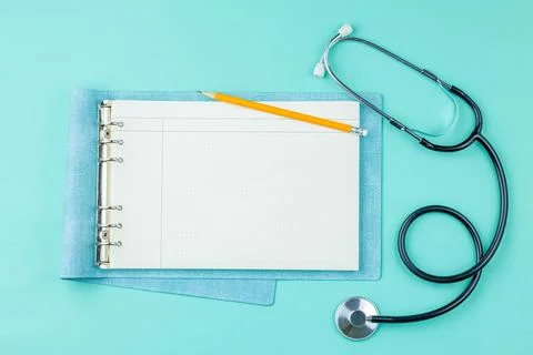 Stethoscope with notepad on green background. Stock Photos