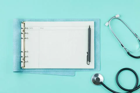 Stethoscope with notepad on green background. Stock Photos