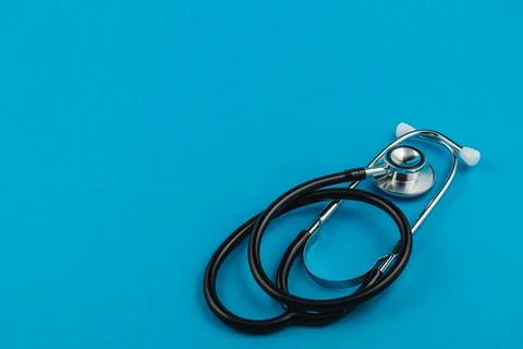 Stethoscope on solid blue background representing healthcare awareness effort Stock Photos