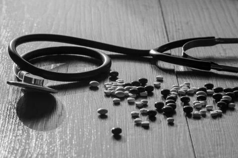 A stethoscope on the table next to the pills Stock Photos