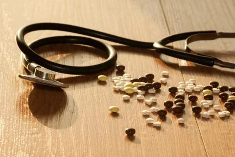 A stethoscope on the table next to the pills Stock Photos
