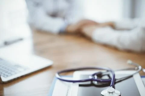 Stethoscope, tablet and laptop computer are lying on the wooden table while 库存照片