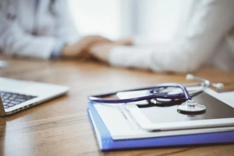 Stethoscope, tablet and laptop computer are lying on the wooden table while 库存照片