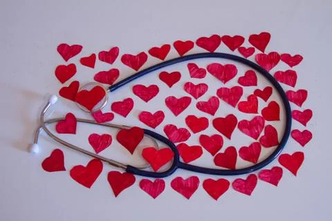 Stethoscope on a white background which is covered with full small hearts co Stock Photos