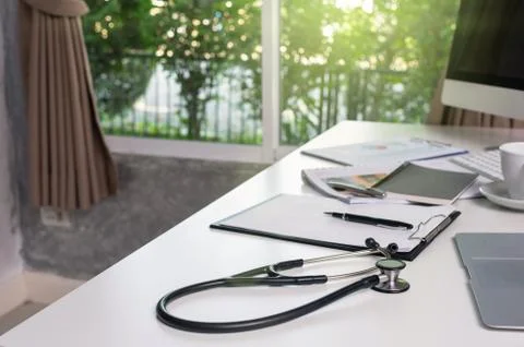 Stethoscope on the workplace table with some part of computer set and keyword Stock Photos
