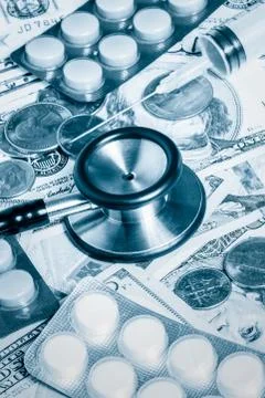 Stethoscope,pills,syringe over a stack of dollars Stock Photos