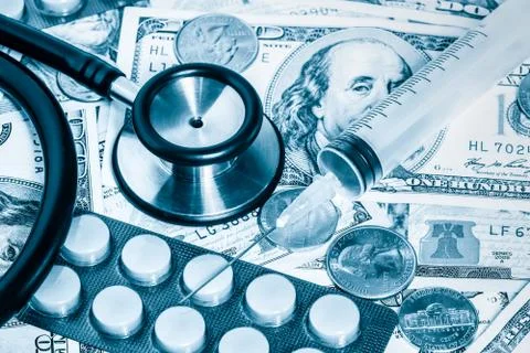 Stethoscope,pills,syringe over a stack of dollars Stock Photos