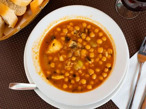 Stew boiled soup prepare of cod fillet, potatoes, chickpeas in tomato sauce. Stock Photos