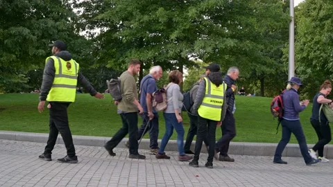 A steward directs people in queue through Jubilee Park Stock Footage 215965367