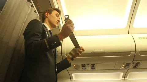 Steward on the plane shows how to use a seat belt Stock Footage 59712982