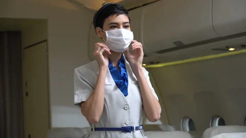 Stewardess demonstrate wearing protective face mask in airplane new normal of Stock Footage 147238641