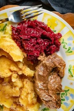 Stewed meat served with mashed potatoes and grated beetroot. Stock Photos