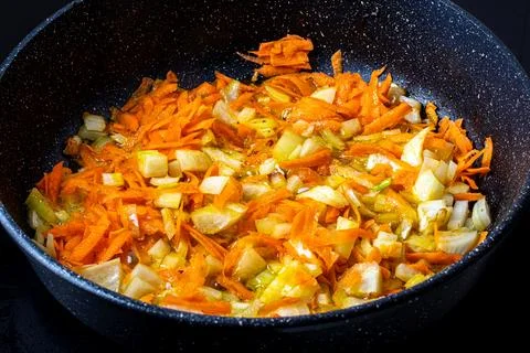 Stewed vegetables in a pan. Cooking process. Vegan food. Stock Photos